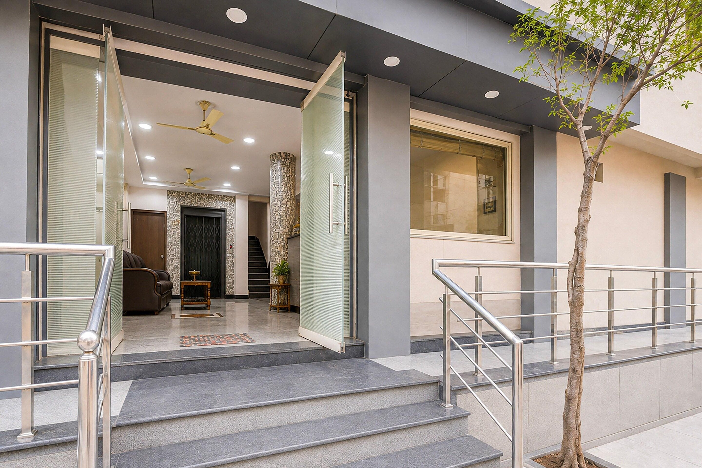 A modern building entrance with a staircase, a ceiling fan, and a potted plant.