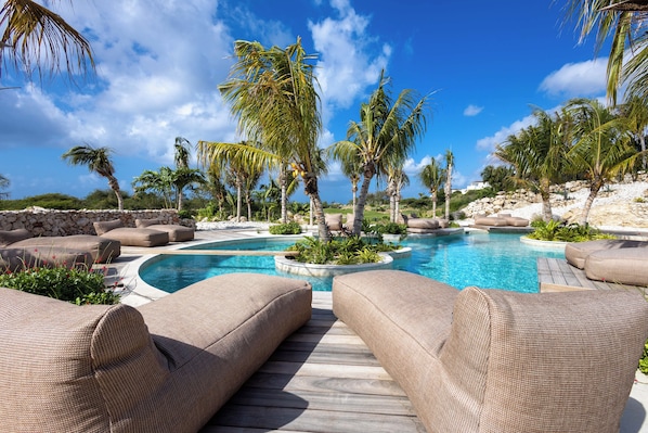 A pool area with lounge chairs and palm trees. - The Reef Superior at Blue Bay (Blue Bay)