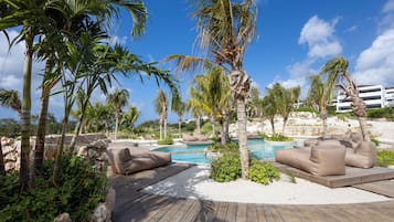A poolside area with palm trees, a wooden deck, and lounge chairs.