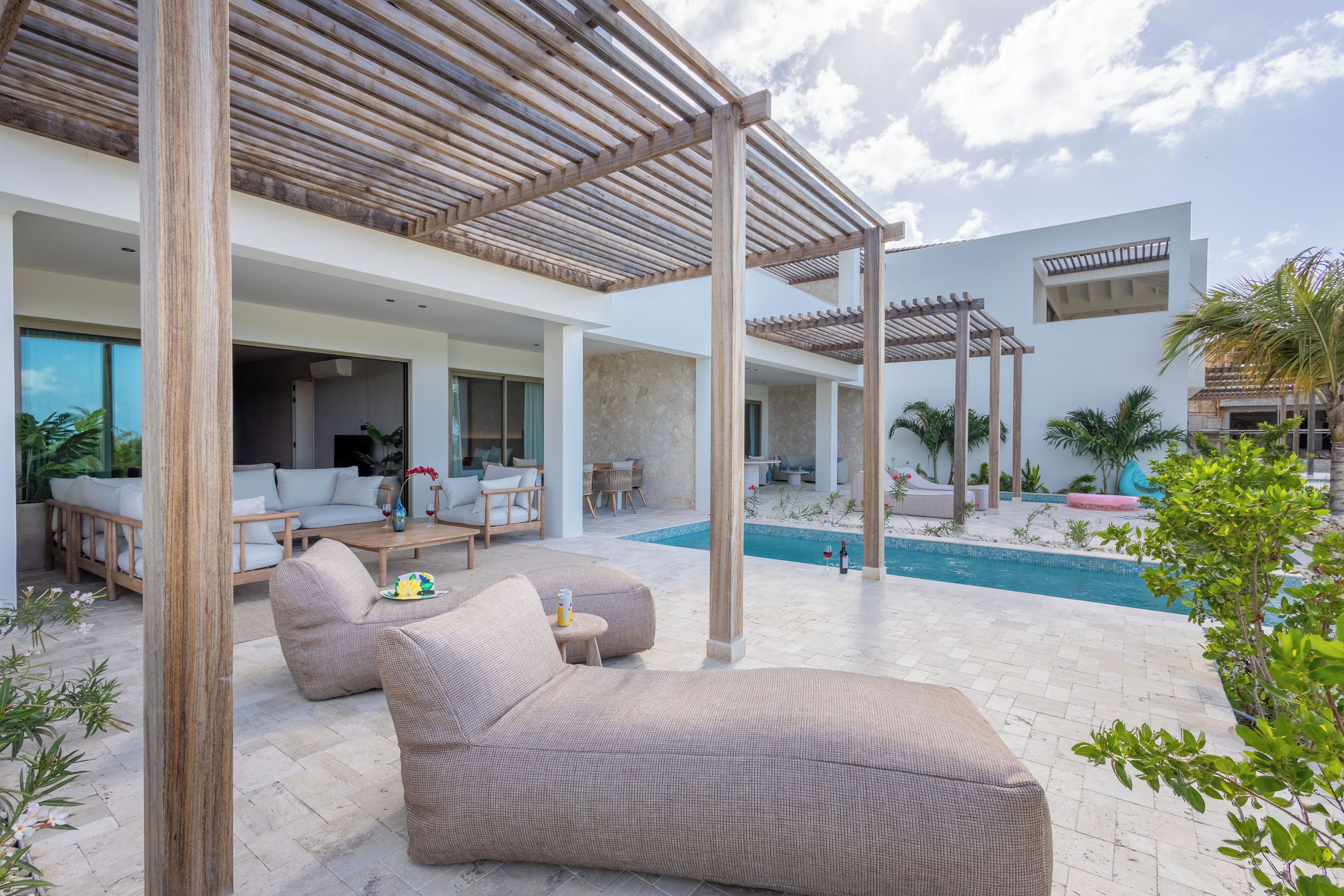 Een moderne buitenlounge met een zwembad, houten pergola's en comfortabele zitplaatsen.