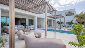Een moderne buitenlounge met een zwembad, houten pergola's en comfortabele zitplaatsen.