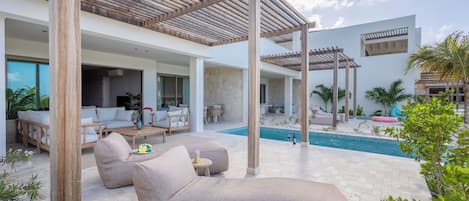Un espacio lounge moderno al aire libre con piscina, pérgolas de madera y asientos cómodos.