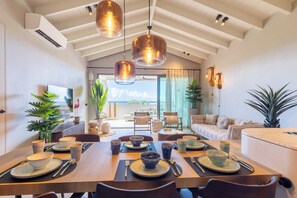 A dining area with a high ceiling, pendant lighting, and a view of the outdoors. - The Reef Superior at Blue Bay (Blue Bay)
