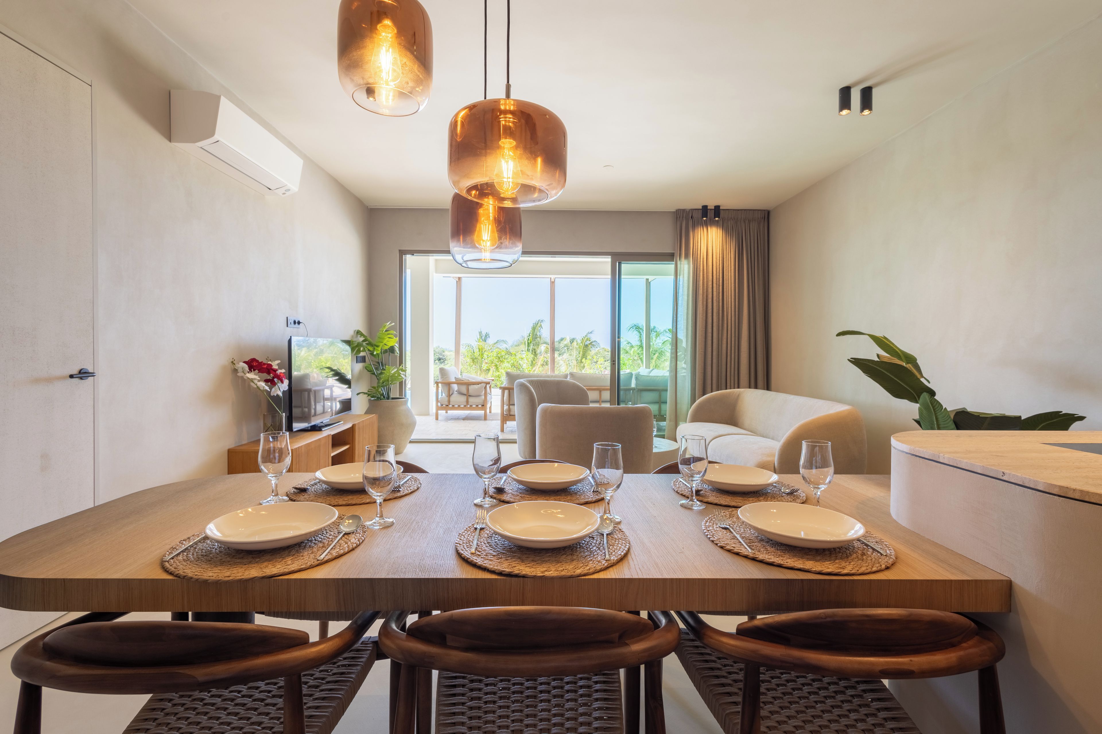 Een eethoek met een ronde tafel voor vier personen, omringd door stoelen, met uitzicht op het buitenlandschap door grote ramen.