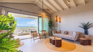 Amplia sala de estar con sofá, sillones y una mesa de centro, con un ventanal y vistas.
