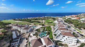 Un resort costero con varias construcciones, una piscina y vista al océano.