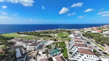 A coastal resort with multiple buildings, a swimming pool, and a view of the ocean.