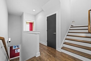 Ein Flur mit einer Holztreppe, einer Tür und einem Fenster mit roten Vorhängen.