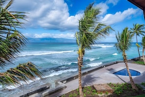 A view of the ocean with waves, palm trees, and a pool area. - Kaanapali, Kulakane, Spacious 4 BR, Beachfront, Sleeps 14 (Lahaina)