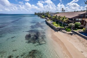 A beachfront property with clear waters, a sandy beach, and a row of buildings with a pool. - Kaanapali, Kulakane, Spacious 4 BR, Beachfront, Sleeps 14 (Lahaina)