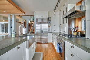 Eine moderne Küche mit Edelstahlgeräten, weißen Schränken und Holzboden.