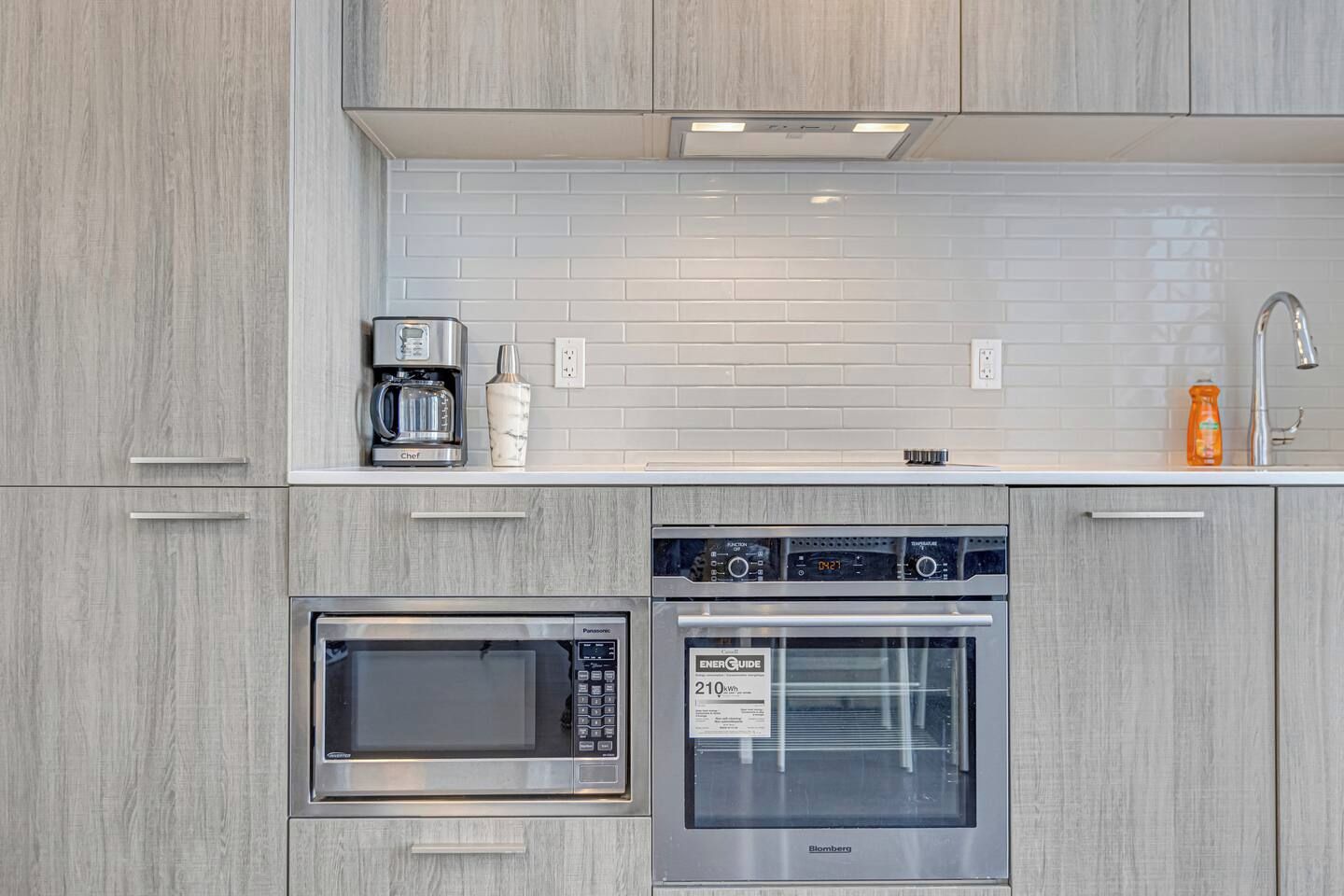 Una cocina moderna con microondas, horno y cafetera integrados.