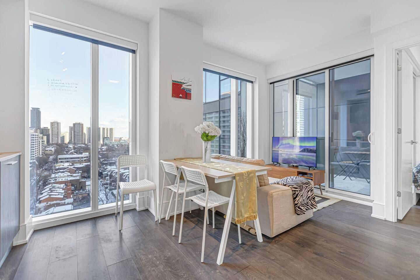 Een moderne woonkamer met een eetgedeelte, grote ramen en uitzicht over de stad.