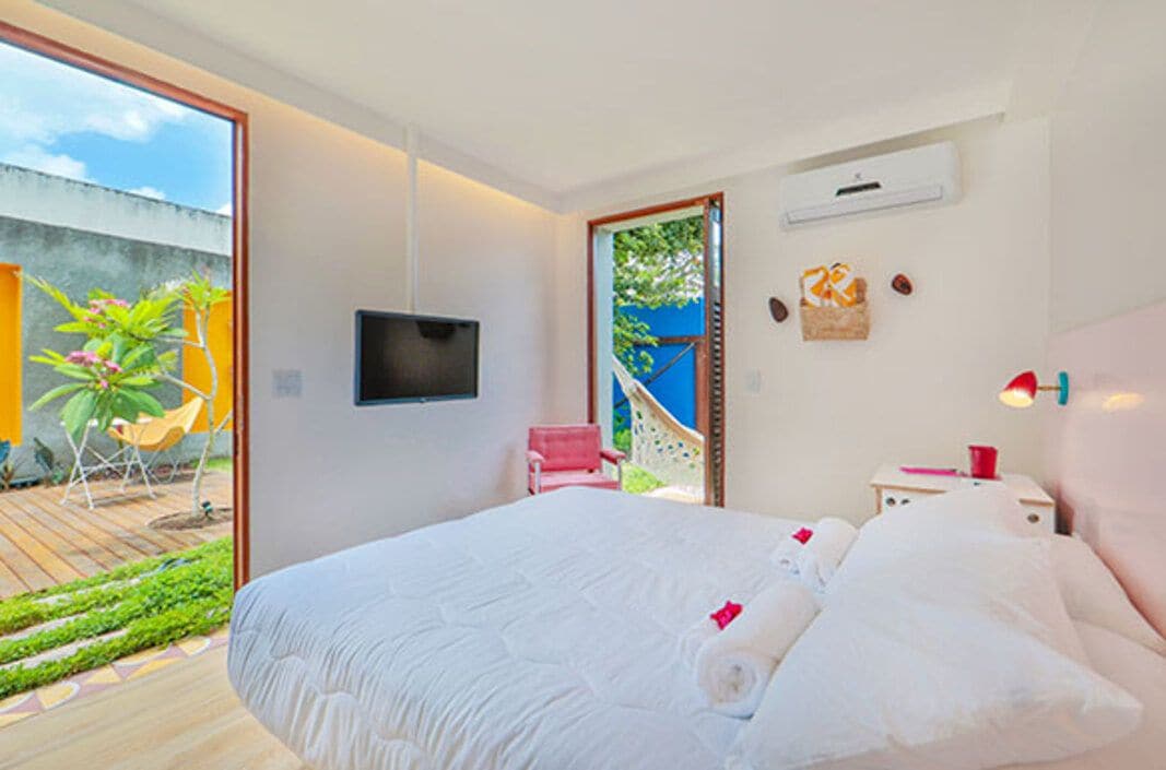 Un dormitorio moderno con una cama grande, un televisor montado en la pared y vistas al exterior.