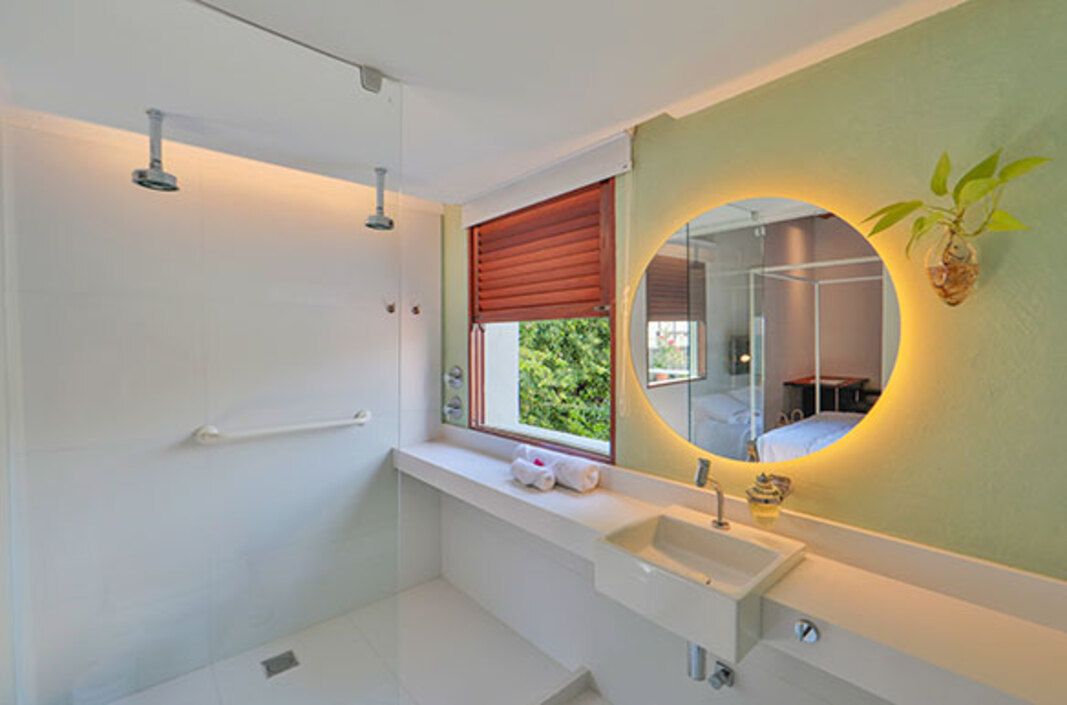 Un baño moderno con ducha, lavamanos y un espejo grande.