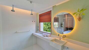 Un baño moderno con ducha, lavamanos y un espejo grande.
