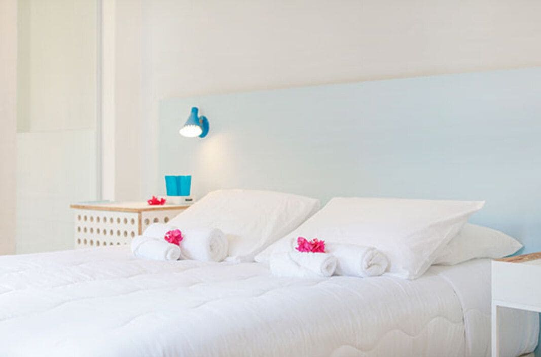 Habitación de hotel con cama, mesita de noche, lámpara y luz en la pared.