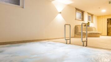 A spa area with a hot tub, a seating area with a cushioned bench, and a wall-mounted mirror.