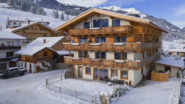 Un edificio de madera de varios pisos con balcones, rodeado por un paisaje nevado y montañas.