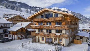 A multi-story wooden building with balconies, surrounded by a snowy landscape and mountains.