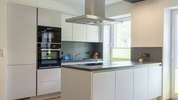 A modern kitchen with a central island, built-in oven, and stainless steel appliances.