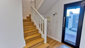 Un escalier en bois avec des rampes blanches menant à une porte dotée d’un cadre noir.