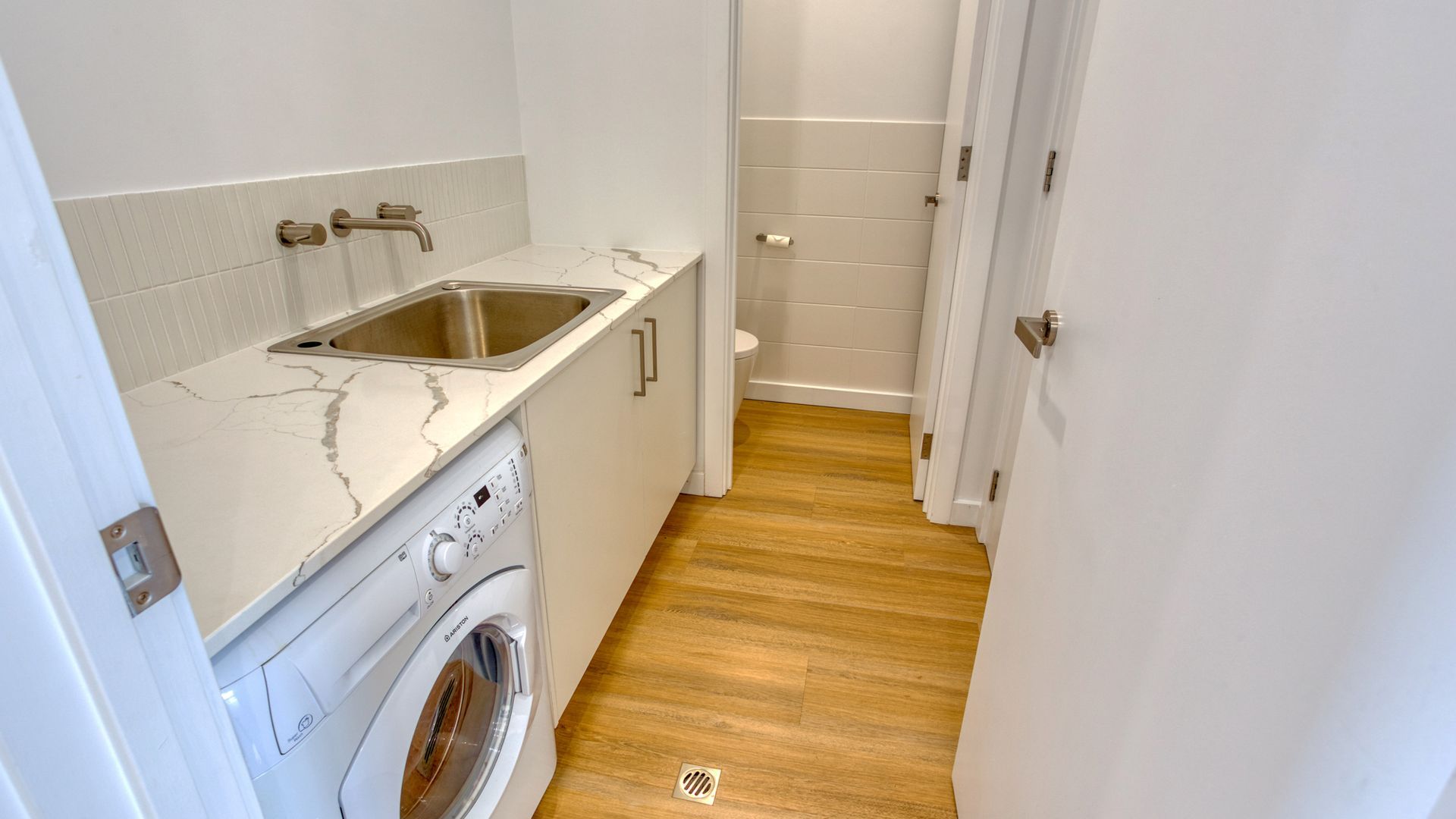Een kleine wasruimte met een wasmachine, een wasbak en een toilet.