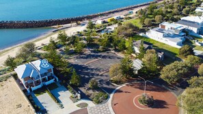 Una vista aerea di una proprietà costiera con un'area di parcheggio, un edificio con tetto blu e una spiaggia sullo sfondo.