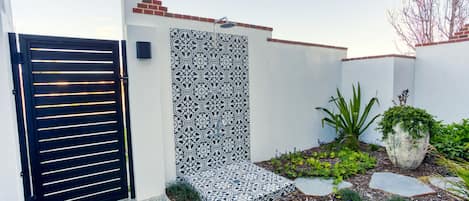 A gated entrance with a decorative wall and a small garden area with plants and stepping stones.