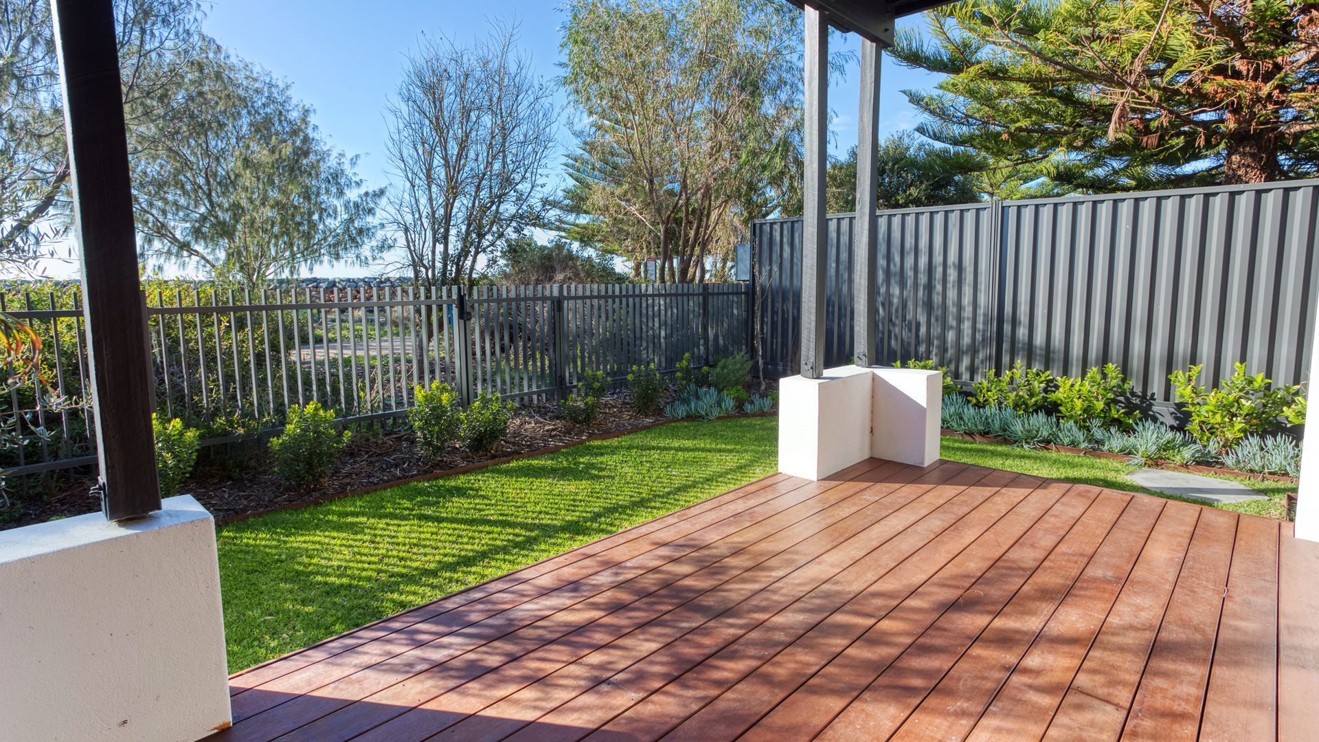 A wooden deck with a metal fence and a grassy area.