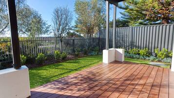 A wooden deck with a metal fence and a grassy area.