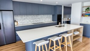 Eine moderne Küche mit Kochinsel, Barhocker und integriertem Backofen.