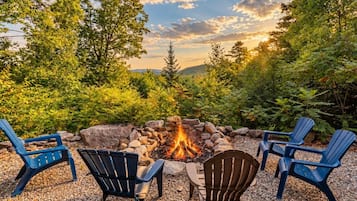 A fire pit surrounded by Adirondack chairs in a natural setting.