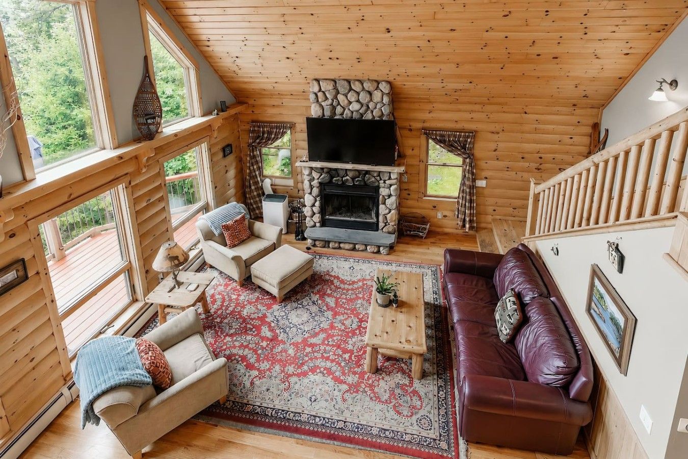 A log cabin interior with a fireplace, wooden floors, a sofa, a coffee table, and a television.