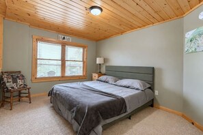 A bedroom with a bed, a nightstand, a chair, a window with blinds, and a ceiling light. - Sleeps 10, Lake View Retreat, with Hot tub & Barrel Sauna (Woodstock)