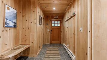 A wooden hallway with a bench, a rug, and a door at the end.