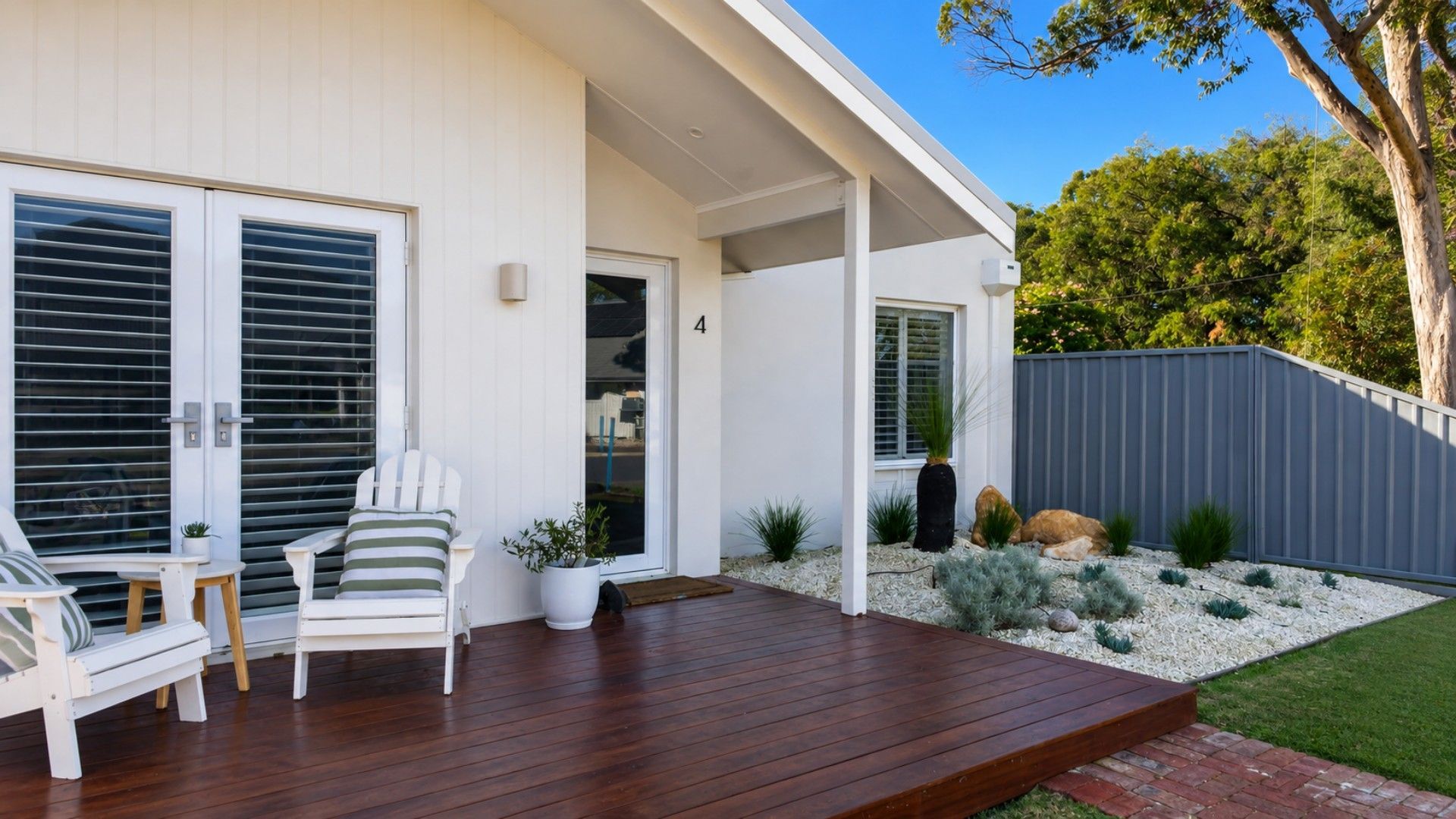 A modern house with a wooden deck, outdoor seating, and a well-maintained garden.