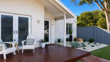 A modern house with a wooden deck, outdoor seating, and a well-maintained garden.