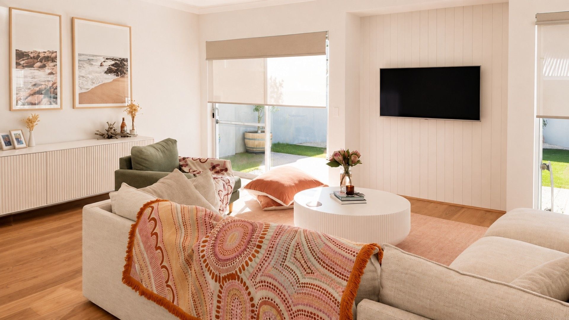 A modern living room with a sofa, a coffee table, and a flat-screen TV mounted on the wall.