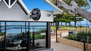 Een restaurant met uitzicht op het water en een brug, met een bord waarop het logo 'KYST' staat.