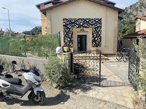 A building with a gated entrance, a parked scooter, and a bicycle.
