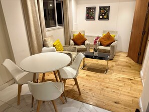 A modern living room with a round dining table, two patterned sofas, and a coffee table with a vase. - The Oak Residence | En-Suite | Canada Water (London)