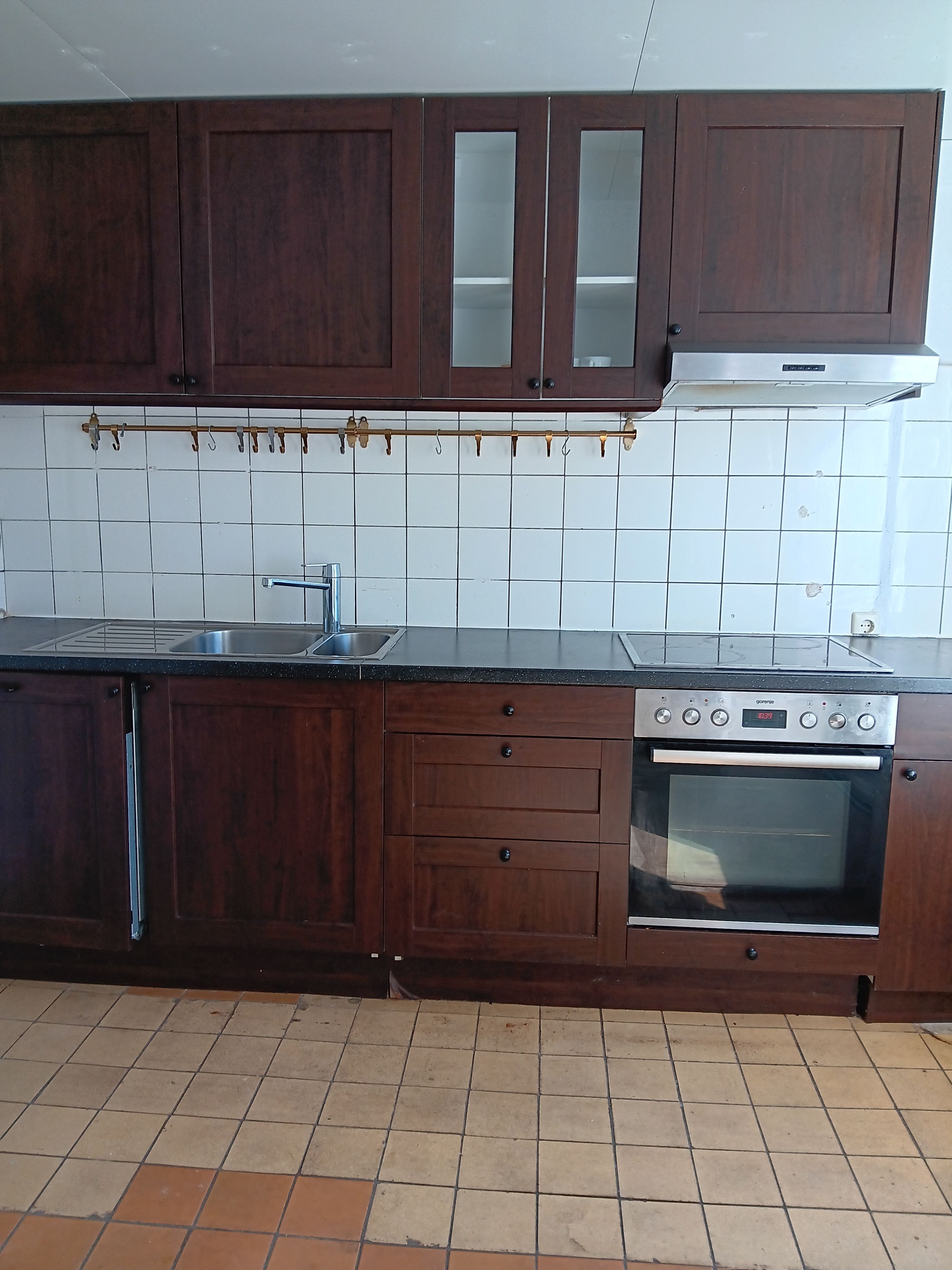 Una cucina con mobili in legno, un lavandino in acciaio inossidabile e un forno integrato.