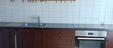 Eine Küche mit Holzschränken, einer Edelstahl-Spüle und einem Einbauofen.