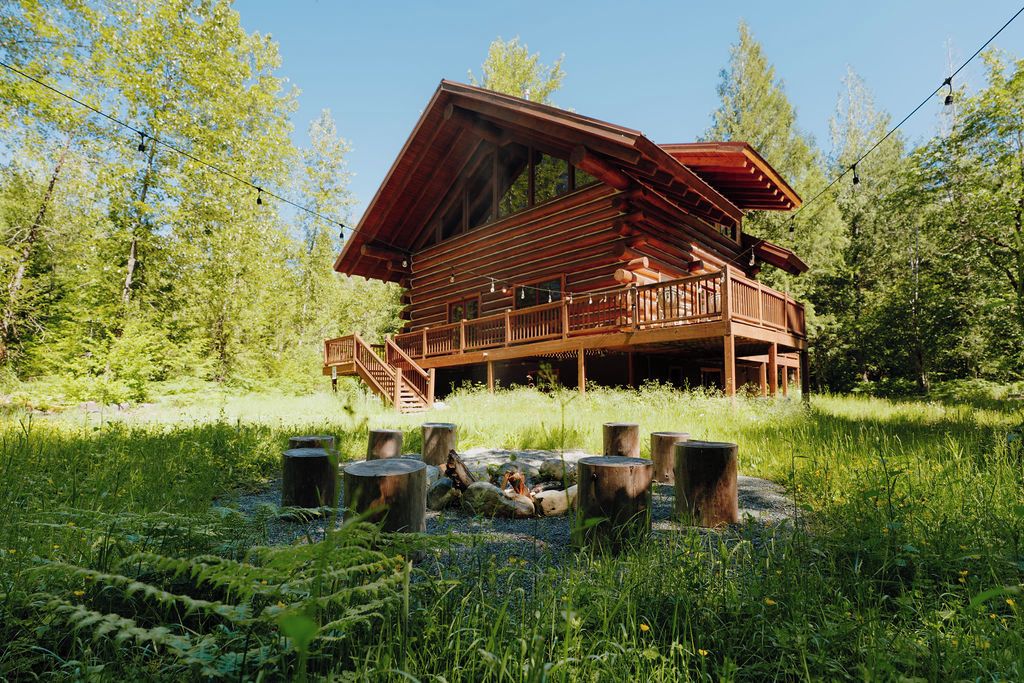 Una cabaña de troncos con terraza, rodeada por un bosque.