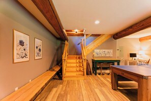 Eine Holztreppe führt zu einer Schlafempore mit einem Tischtennisch und einem Schreibtisch.