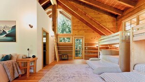 Eine Holzhütte mit Schlafzimmer im oberen Bereich, Holzböden, einem Etagenbett und Blick ins Freie.