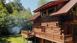 Eine Blockhütte mit Balkon, umgeben von Bäumen.