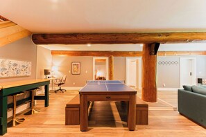 Ein Tischtennistisch in einem Raum mit Holzboden, einem grünen Sofa und einer Holzbalkendecke.