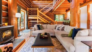 Ein Blockhaus-Interieur mit Kamin, einer Couch und einer Treppe.